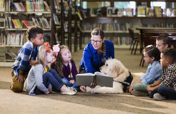 Children in library with reading assistance dog